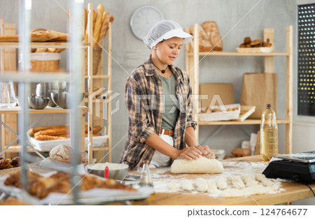 Woman works in bakery as baker, kneads dough, works with flour. Woman works in bakery as baker, kneads dough, works with flour. 124764677
