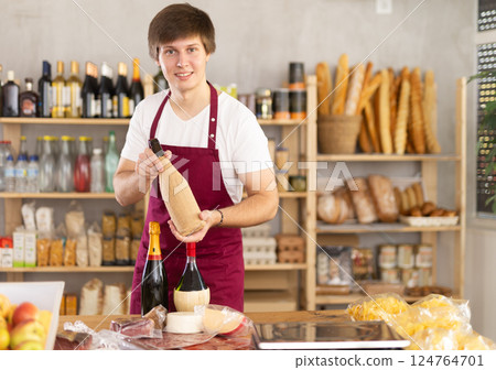 Guy employee sells alcohol drink wine, and offers wide range of snack, nutrition. 124764701