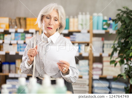 Elderly woman chooses prescription pills at pharmacy 124764749
