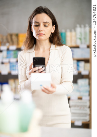 Woman in pharmacy scans QR code on cream product Woman in pharmacy scans QR code on cream product 124764821