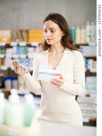Girl in summer clothes looking for medicine in pharmacy 124764832