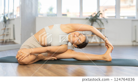 Young woman doing stretching Parivrtta Janu Sirsasana asana Young woman doing stretching Parivrtta Janu Sirsasana asana 124764836