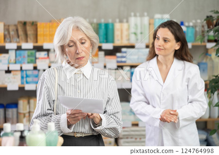 Mature woman with medical prescription on pharmacist background 124764998