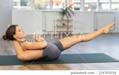 Lover of active lifestyle on yoga mat perform doing yoganidrasan in gym Lover of active lifestyle on yoga mat perform doing yoganidrasan in gym 124765038