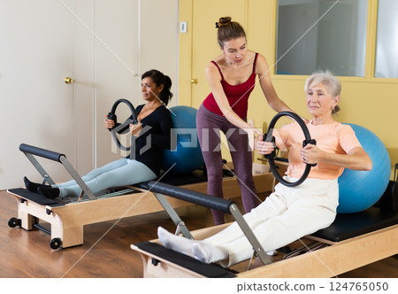 Two women perform an exercise using special rings and a fitball Two women perform an exercise using special rings and a fitball 124765050