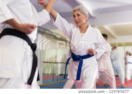 Elderly woman in kimono practicing martial arts techniques with trainer Elderly woman in kimono practicing martial arts techniques with trainer 124765077