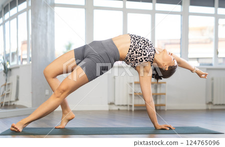 Yoga in sports gym. Girl performs side plank asana, vasishthasana 124765096