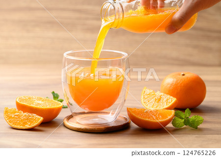 Orange juice pouring into glass with orange fruit on wooden background, Healthy drink 124765226