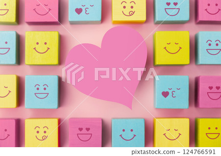 Love and Human Relationship Concepts. Happy Community. Pastel Pink Heart Shape surrounded by Group of Smiling Emoticon Diversity Face on Cube. Table Top View 124766591