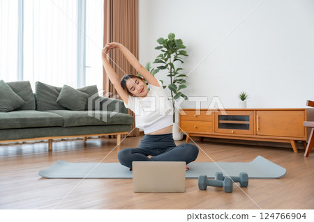 Happy young Asian woman practicing yoga and shoulder stretching at home 124766904