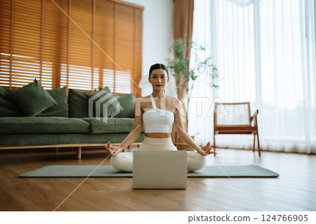 Young Asian woman meditating in lotus position at home 124766905