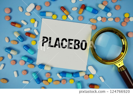 Placebo text on sticky note paper with Medicine and Magnifying glass on blue background Placebo text on sticky note paper with Medicine and Magnifying glass on blue background 124766920