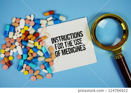 Instructions for the Use of Medicines text on sticky note paper with Medicine and Magnifying glass on blue background Instructions for the Use of Medicines text on sticky note paper with Medicine and Magnifying glass on blue background 124766922