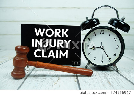 Work Injury Claim text on paper card with alarm clock and wooden judge gavel on wooden background Work Injury Claim text on paper card with alarm clock and wooden judge gavel on wooden background 124766947