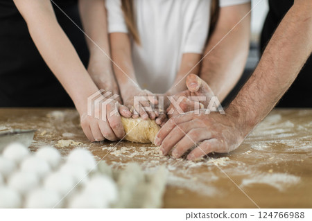 Caucasian family bonding through cooking activity, kneading dough with children and adults together 124766988