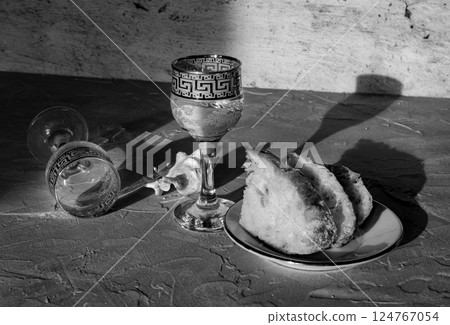 A glass of vodka, sliced bread and a seashell casting long shadows, in black and white A glass of vodka, sliced bread and a seashell casting long shadows, in black and white 124767054