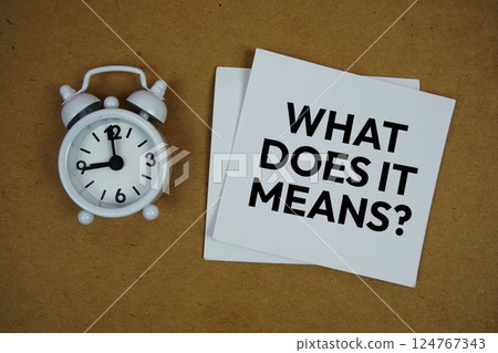 What does it mean? text on sticky note with alarm clock on paper craft background 124767343