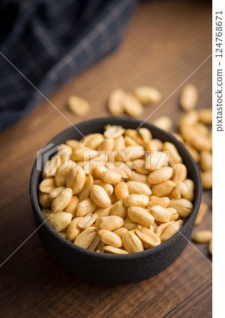 Roasted salted peanuts in bowl on wooden table. Roasted salted peanuts in bowl on wooden table. 124768671