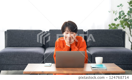 一名中年婦女在筆記型電腦上觀看直播時鼓掌 一名中年婦女在筆記型電腦上觀看直播時鼓掌 124768714