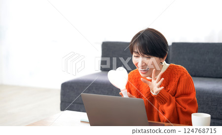 A middle-aged woman watching a live broadcast on her laptop computer A middle-aged woman watching a live broadcast on her laptop computer 124768715