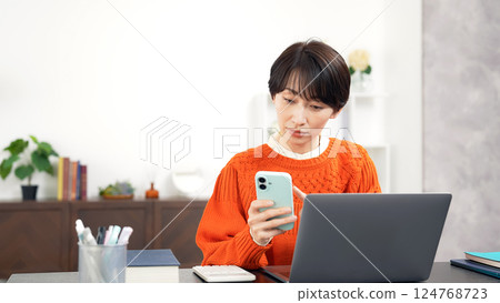 使用智慧型手機和筆記型電腦的中年婦女 使用智慧型手機和筆記型電腦的中年婦女 124768723