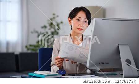 A female business person working on a computer in a dark office A female business person working on a computer in a dark office 124768757