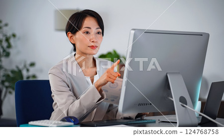 A female business person working on a computer in a dark office A female business person working on a computer in a dark office 124768758
