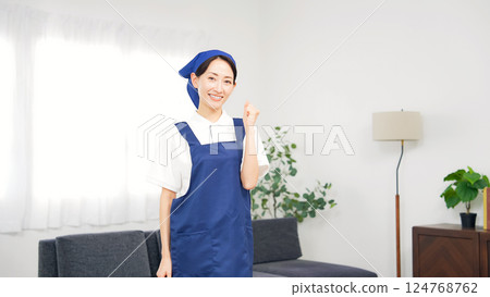 A middle-aged woman wearing an apron pumping her fist in the living room 124768762