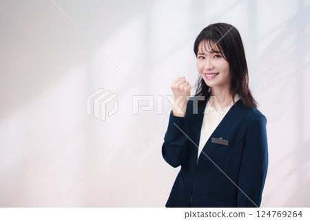 一位戴著名牌、面帶微笑為顧客服務的年輕女士（背景簡單） 124769264