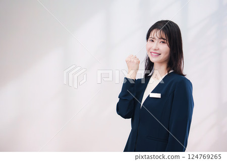 一位戴著名牌、面帶微笑為顧客服務的年輕女士（背景簡單） 124769265
