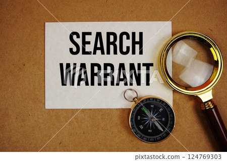 Search Warrant text on paper torn with compass and magnifying glass on paper craft background 124769303