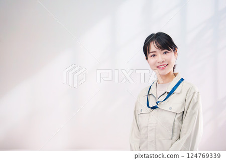 A smiling young woman wearing work clothes (simple background) A smiling young woman wearing work clothes (simple background) 124769339