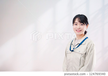 A smiling young woman wearing work clothes (simple background) A smiling young woman wearing work clothes (simple background) 124769340