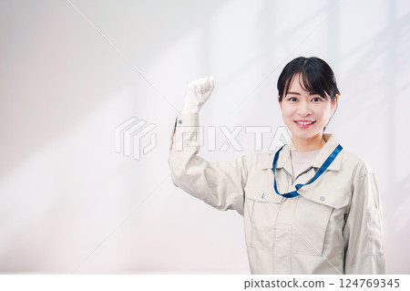 A smiling young woman wearing work clothes (simple background) A smiling young woman wearing work clothes (simple background) 124769345
