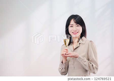 微笑的年輕女子喝氣泡酒（簡單的背景） 124769521