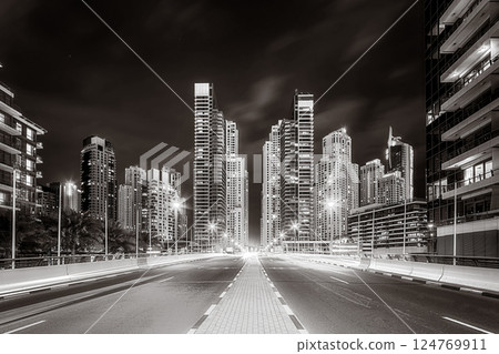 Urban city skyline with illuminated skyscrapers and waterfront railing in black and white at night, Dubai Marina bay UAE Urban city skyline with illuminated skyscrapers and waterfront railing in black and white at night, Dubai Marina bay UAE 124769911
