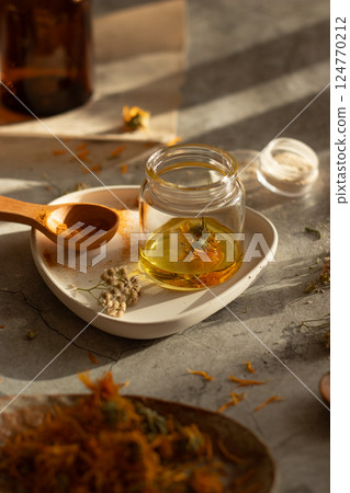 Side view of different wild herbal medicinal plants, oils, turmeric powder, gathered on a table in a process of preparation calendula, yarrow 124770212