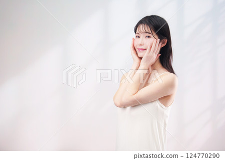 A young woman smiling and taking care of her skin (simple background) A young woman smiling and taking care of her skin (simple background) 124770290