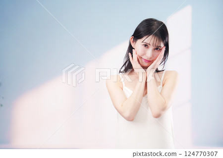 A young woman smiling and taking care of her skin (simple background) A young woman smiling and taking care of her skin (simple background) 124770307