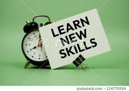 Learn New Skills text message on paper card with alarm clock on green background 124770584