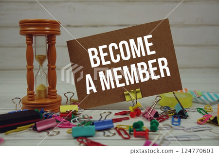 Become A Member text on paper card with hourglass and stationary on wooden background 124770601