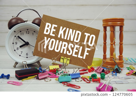 Be Kind To Yourself text on paper card with alarm clock and stationary on wooden background Be Kind To Yourself text on paper card with alarm clock and stationary on wooden background 124770605