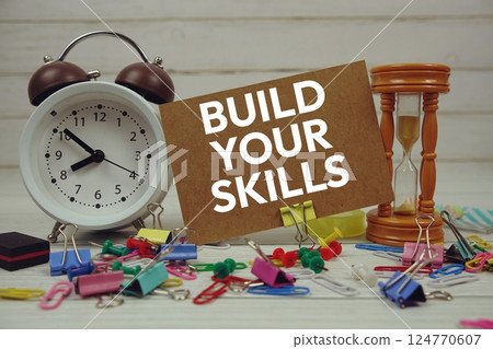 Build Your Skills text on paper card with alarm clock and stationary on wooden background 124770607