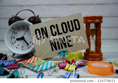 On Cloud Nine text on paper card with alarm clock and stationary on wooden background 124770613