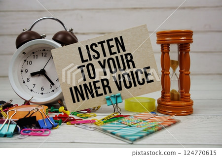Listen to your inner voice text on paper card with alarm clock and stationary on wooden background 124770615