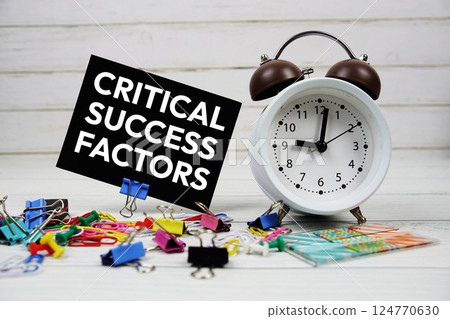 Critical Success Factors text on paper card with alarm clock and stationary on wooden background 124770630