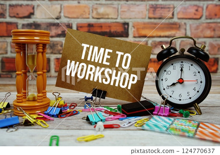 Time To Workshop text on paper card with alarm clock and stationary on wooden background Time To Workshop text on paper card with alarm clock and stationary on wooden background 124770637