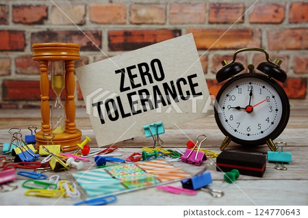 Zero Tolerance text on paper card with alarm clock and stationary on wooden background Zero Tolerance text on paper card with alarm clock and stationary on wooden background 124770643