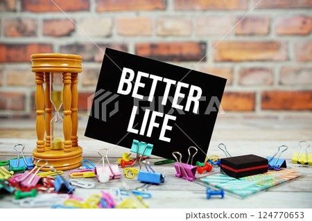 Better Life text on paper card with hourglass and stationary on wooden background Better Life text on paper card with hourglass and stationary on wooden background 124770653
