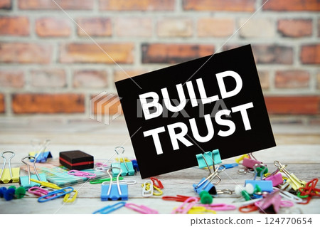Build Trust text on paper card with stationary on wooden background 124770654
